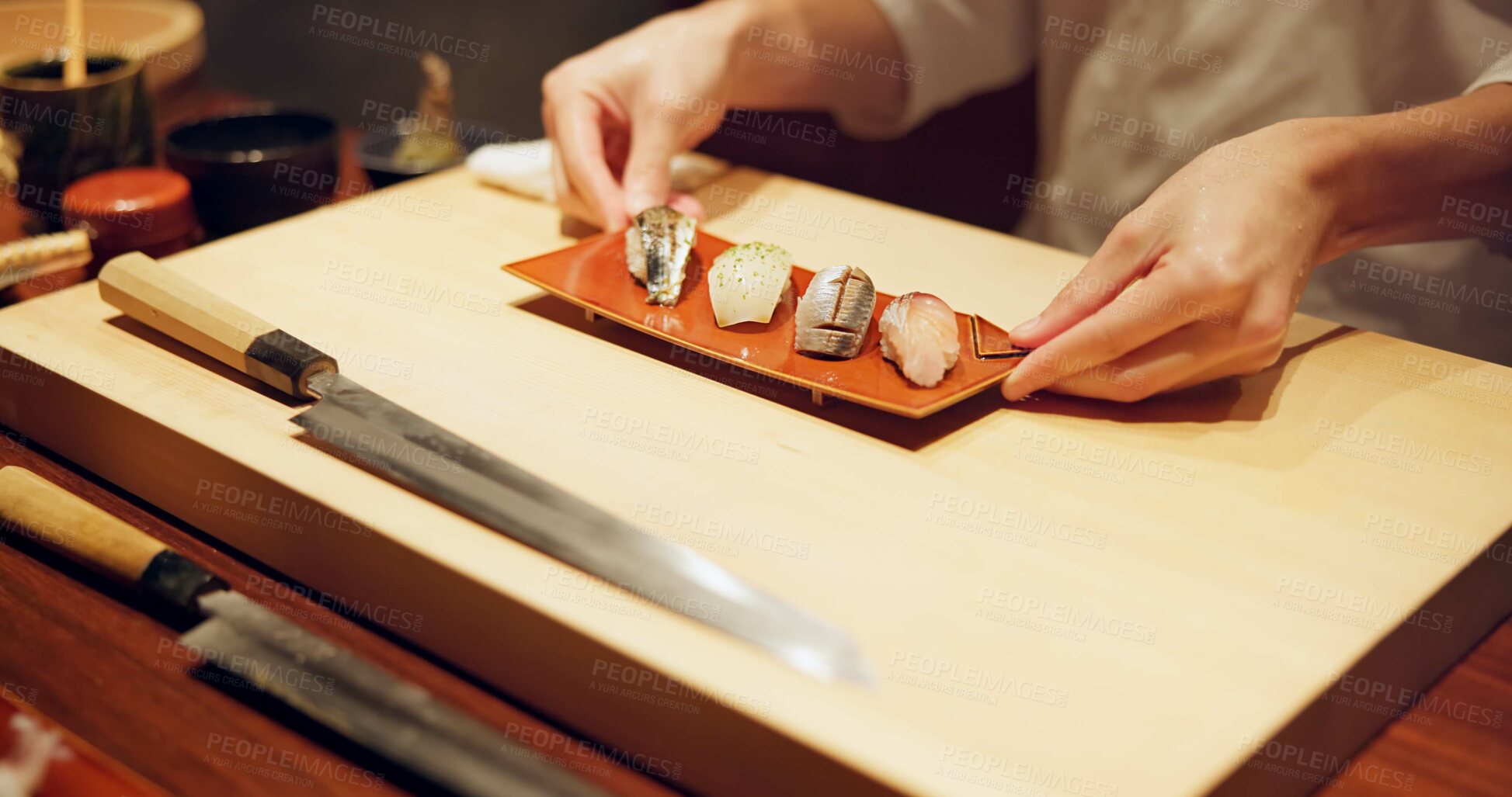 Buy stock photo Hands, food and chef serving sushi in restaurant for traditional Japanese cuisine or dish closeup. Kitchen, cooking or seafood preparation and person working on table with gourmet meal ingredients