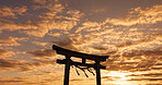 Torii gate, sunset sky in Japan with nature, zen and spiritual history on travel adventure. Shinto architecture, Asian culture and calm clouds on Japanese landscape with sacred monument at shrine.