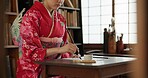 Ink, writing and hands of Japanese woman for traditional script on paper, documents and page. Creative, Asian culture and person with vintage paintbrush tools for calligraphy, font and text in home