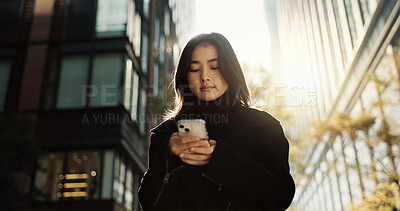 Walking, phone and Japanese woman in the city networking on social media, mobile app or the internet. Travel, adventure and young female person commuting in road with cellphone town in Kyoto Japan.