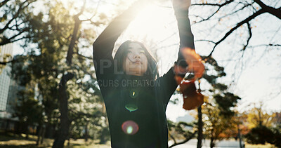 Buy stock photo Playful, leaves, and woman with arms raised, sunshine and nature with lens flare, relaxing and peaceful. Person, outdoor and girl in autumn, fresh air and wellness with weekend break and freedom