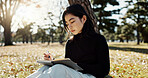 Japanese woman, reading and book in park, thinking and relax by tree, grass or sunshine with peace. Girl, person or student with story in nature, college or idea with vision, knowledge or campus lawn