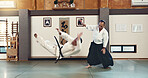 Aikido, sensei and fight with a master in martial arts with student in self defence, discipline and training. Demonstration, class or Japanese man with black belt in fighting with education of skill