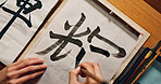 Hands writing, brush and Asian font for art and script, calligraphy with closeup of alphabet. Japanese, creative person or top view of vintage tools, paintbrush and stroke with traditional stationery
