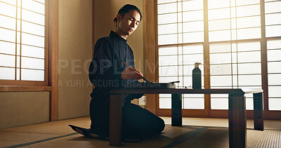Man, calligraphy or creative Japanese artist in studio for art and script, letter with table, paper or alphabet. Asian, brush or person with tools, paintbrush and focus with traditional stationery