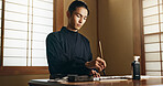 Calligraphy, ink and traditional Japanese man with paper for letters, notes and text for documents or script. Creative, writer and person with paintbrush, tools and desk for art, writing and culture