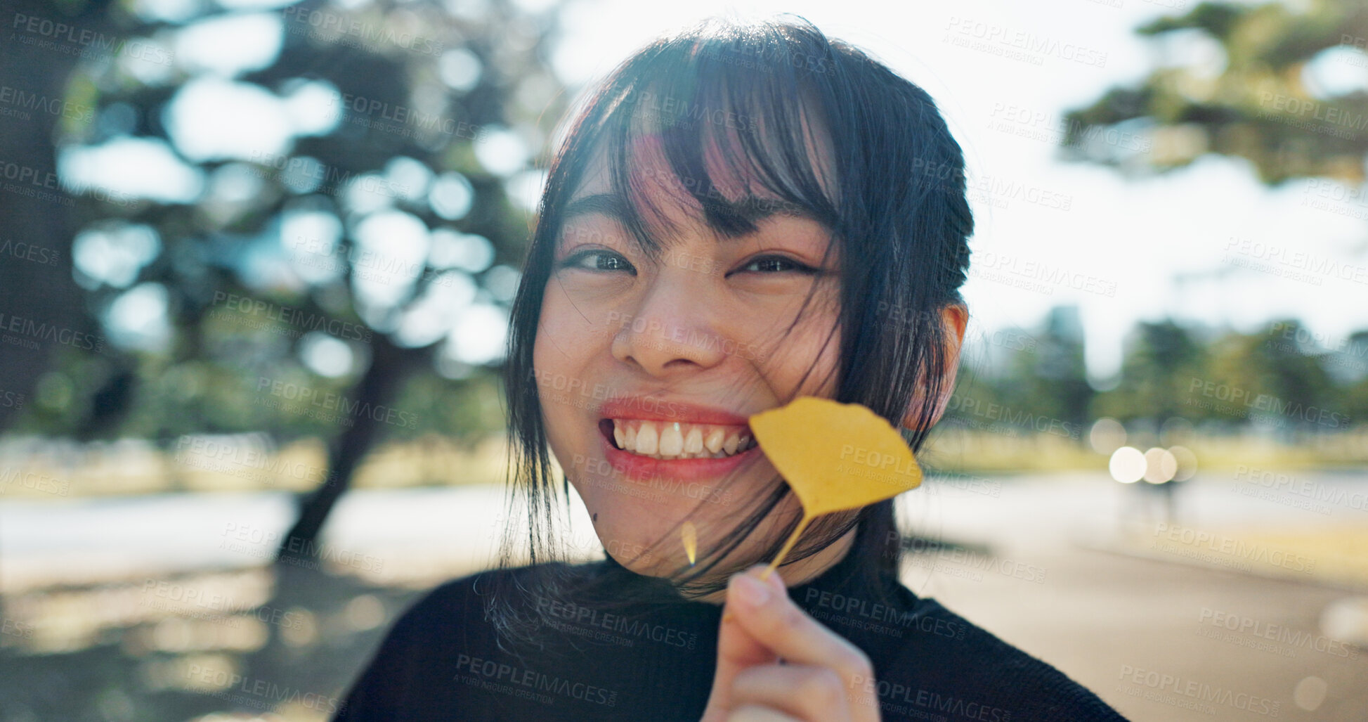 Buy stock photo Asian, happy woman in park and leaf with face and explore nature for wellness and outdoor environment. Sunshine, plants and portrait, travel and adventure in public garden with smile on journey