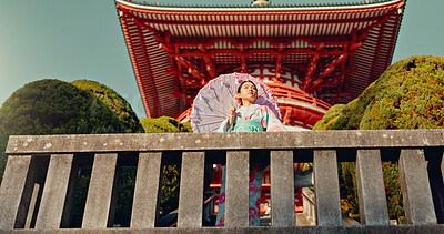 Japanese woman, umbrella and shinto temple with traditional clothes, culture and religion in sunshine. Person, girl and parasol for walk with faith, mindfulness and thinking with low angle in Kyoto