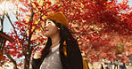 Asian woman, autumn trees and walking in Japan for natural scenery, adventure or journey in nature. Female person smile with backpack or bag for outdoor trip with blooming plants or leaves in season