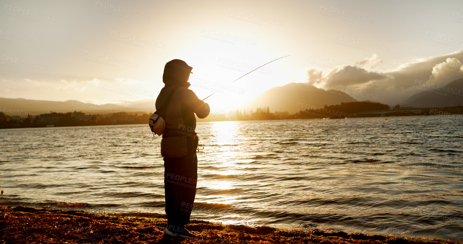 Buy stock photo Person, fishing and water in morning, sunrise and sport by ocean, lake and river with equipment in nature. Fisherman, line and catch fish for games, food and silhouette in sunshine, dawn and horizon
