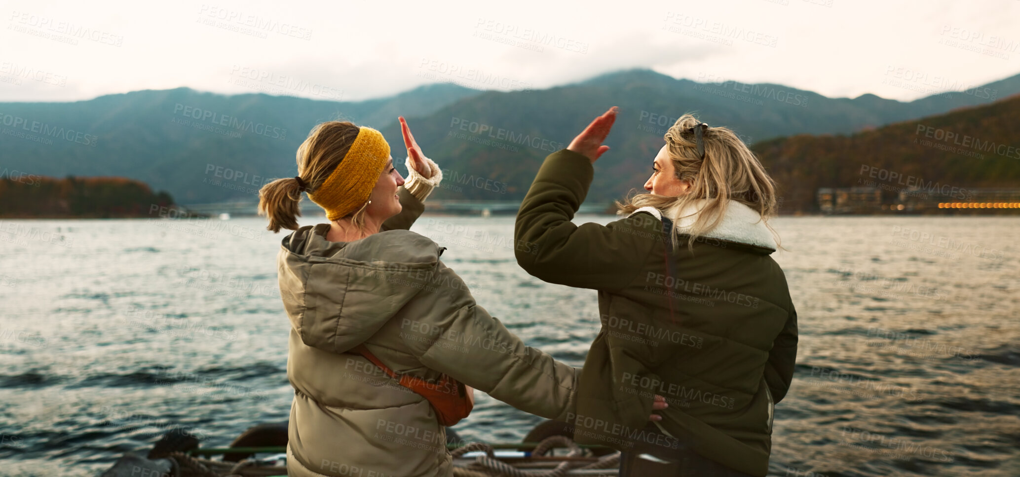 Buy stock photo Women friends, hug and back at beach with care, love and outdoor with high five, support or celebration on travel. Girl, cheers and achievement with boat, water or lake with bonding by river in Japan