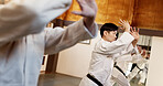 Students, people or learning martial arts in dojo for practice, aikido movement or self defense together. Combat demonstration, fitness exercise or training workout for fighting, education or class