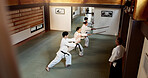 Aikido students, stick or learning martial arts in dojo for practice, movement or self defense. Combat demonstration, above or Japanese people in training workout for fighting, education or sensei