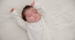 Newborn, face or sleeping with stretching on bed in nursery for relaxing or resting with child development. Baby, tired or dreaming in bedroom of house with calm, relax and cute infant in family home