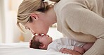Happy, mother and baby kiss with love, care and support in a home with newborn and bonding. Morning, mom and relax infant with child security and motherhood in a family home on a bed with mama