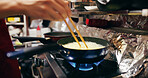 Cooking, chopsticks and person with pan on gas stove at market for meal preparation, eating and nutrition. Culinary, flame and closeup of chef hands with utensils for egg cuisine, dinner and supper