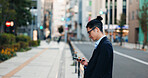 Phone, networking and Japanese businessman in the city reading company email on technology. Career, travel and professional young male person scroll or browse on cellphone with earbuds in urban town.