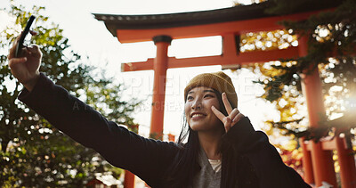 Selfie, nature and Japanese woman with peace sign for holiday, vacation and adventure in Japan. Happy, travel and person take picture on smartphone for social media post, memories and online blog