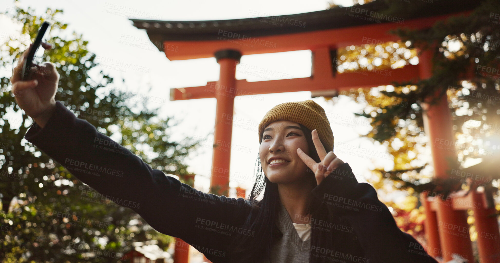 Buy stock photo Selfie, torii gate and Japanese woman with peace sign in forest for holiday adventure in Japan. Happy smile, woods and girl with digital photography, social media post and memory for travel blog.