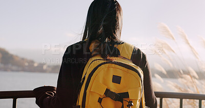 Woman, water and backpack with back, thinking and mountains on adventure, trip or vacation in nature. Girl, person and ideas on holiday with bag, vision and memory by lake, river and bridge in Tokyo