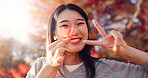 Japanese woman, face and leaf from park with peace sign, happiness and autumn adventure and holiday. Girl, plant and memory of vacation in forest, environment or outdoor with leaves in Kyoto Japan