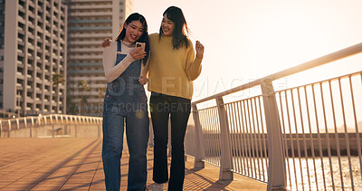 Walking, women and friends with cellphone, outdoor and happiness with social media, connection or sunshine. People, Japan or hug with smartphone, promenade or funny with network, smile or digital app