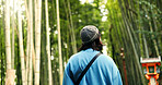 Back, travel and person at bamboo forest outdoor, nature or park in Ariyishiyama, Kyoto, Japan. Rear view of tourist in green garden, environment and sightseeing in jungle adventure on summer trip