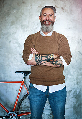 Buy stock photo Portrait of a middle aged man standing with his arms folded with a red bicycle in the back against a grey background