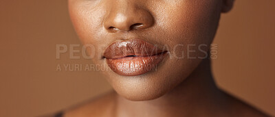 Closeup, lips and black woman with beauty, smile and skincare on a brown studio background. African person, girl and model with gloss, cosmetics and dermatology with clear skin, smooth and aesthetic