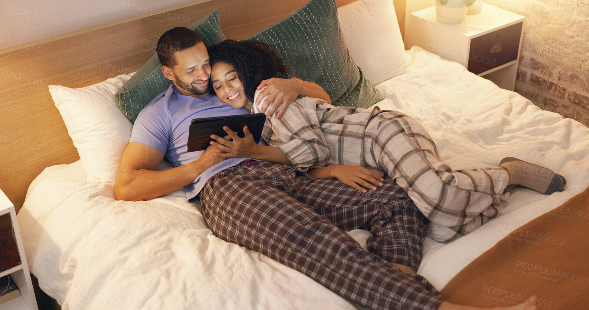 Buy stock photo Couple, happy and hug in bedroom with tablet at night, streaming movie and relax. Smile, technology and man and woman in bed on social media app, watching online video and bonding together in home.