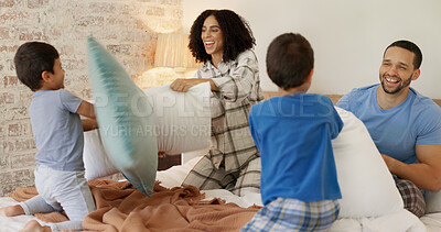 Happy family, pillow fight and bedroom with kids, playing and excited with love, bonding and care in home. Man, woman and boy children on bed for game, playful conflict or comic quality time in house