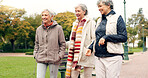 Senior friends, talking and walking together on an outdoor path to relax in nature with elderly women in retirement. Happy, people pointing and conversation in the park or woods in autumn or winter