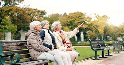 Happy, senior friends and walking together on an outdoor path or relax in nature with elderly women in retirement. People, talking and sitting for conversation on a park bench in autumn or winter