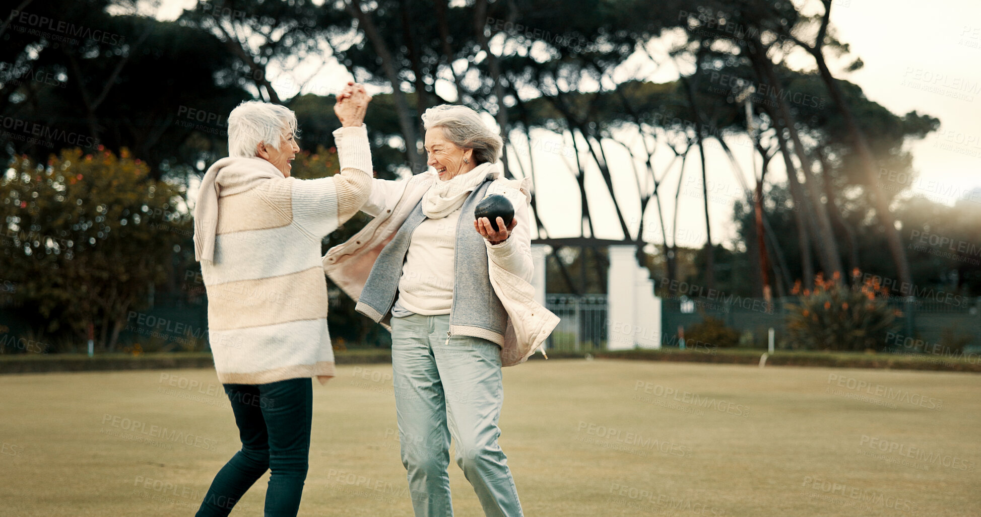 Buy stock photo Senior women, high five and park for sport, lawn bowling and happy for fitness, goal and celebration in nature. Teamwork, elderly lady friends and metal ball for games, contest and winning together