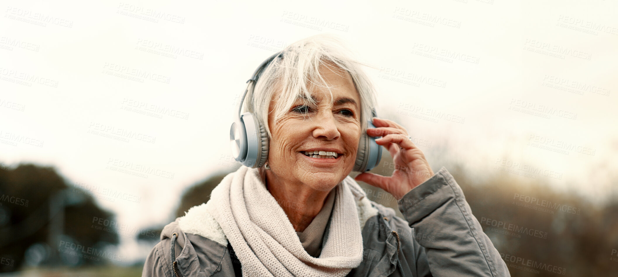 Buy stock photo Old woman, headphones and listening to music outdoor, walking and wellness with audio streaming and energy. Podcast, radio and sound with female person on city bridge, exercise and travel with tech