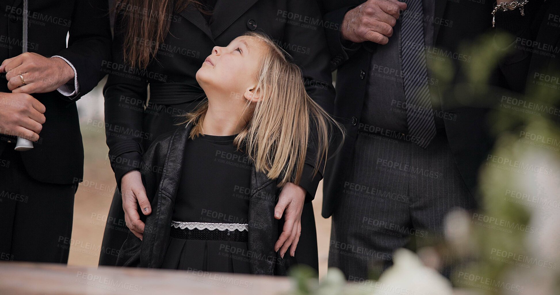 Buy stock photo Mourning, grief and family with girl at funeral, flowers on coffin, death and sad child at service in graveyard. Support, loss and people at casket in cemetery with kid crying at grave for burial.