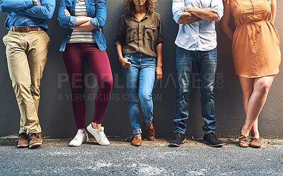 Buy stock photo Shot of a group unrecognizable people leaning against a wall while posing for a photo outside