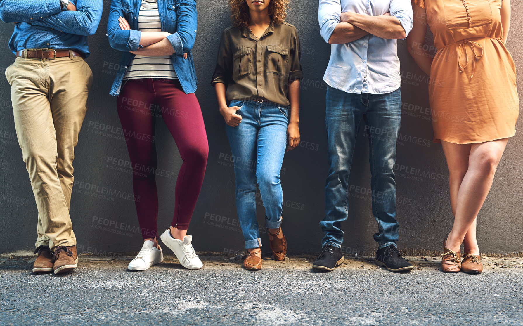 Buy stock photo Shot of a group unrecognizable people leaning against a wall while posing for a photo outside