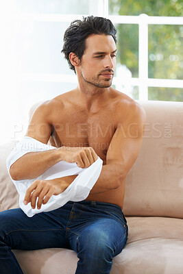 Buy stock photo Fashion, body and a young man dressing on a sofa in the living room of his home while thinking in the morning. Clothes, style and casual with a shirtless male person getting ready in an apartment