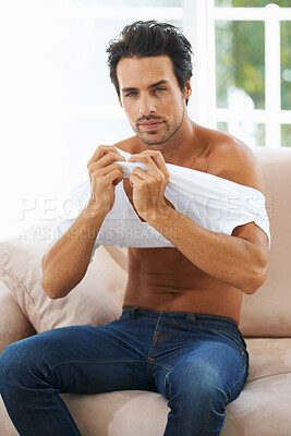 Buy stock photo Portrait, body and a young man dressing on a sofa in the living room of his home for fashion in the morning. Clothes, style and confident with a shirtless young person getting ready in an apartment