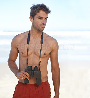 Buy stock photo Man, binoculars and lifeguard on beach for security, emergency or health and safety. Face of young male person in fitness for monitoring, bay watch or patrol by the ocean coast or sea in surveillance