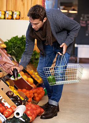 Buy stock photo Healthy food, search and man shopping at a supermarket for grocery promotions, sale or discounts deal. Check, fresh or customer buying groceries for fruits, organic vegetables or eggplant with choice