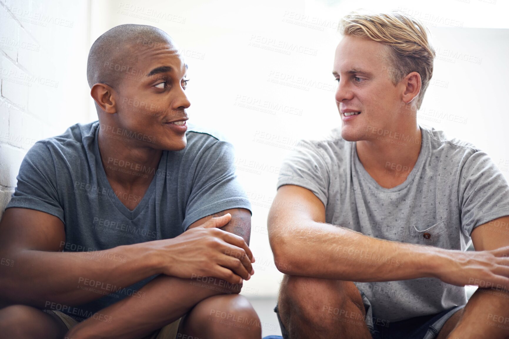 Buy stock photo Shot of male university students sitting and talking before class