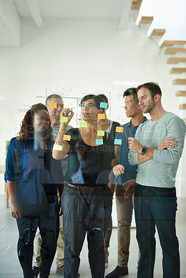Buy stock photo Diverse team of creative designers brainstorming and planning in an office together using sticky notes. Group leader and casual employees working on a schedule and developing ideas and business goals