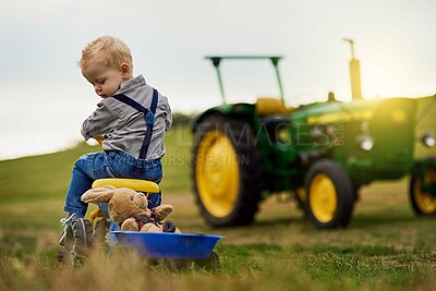 Buy stock photo Shot of an adorable little boy carting stuffed animals in a toy truck around a farm