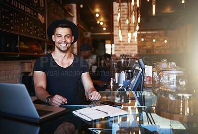 Buy stock photo Shot of a handsome young man working behind the counter of a coffee shop