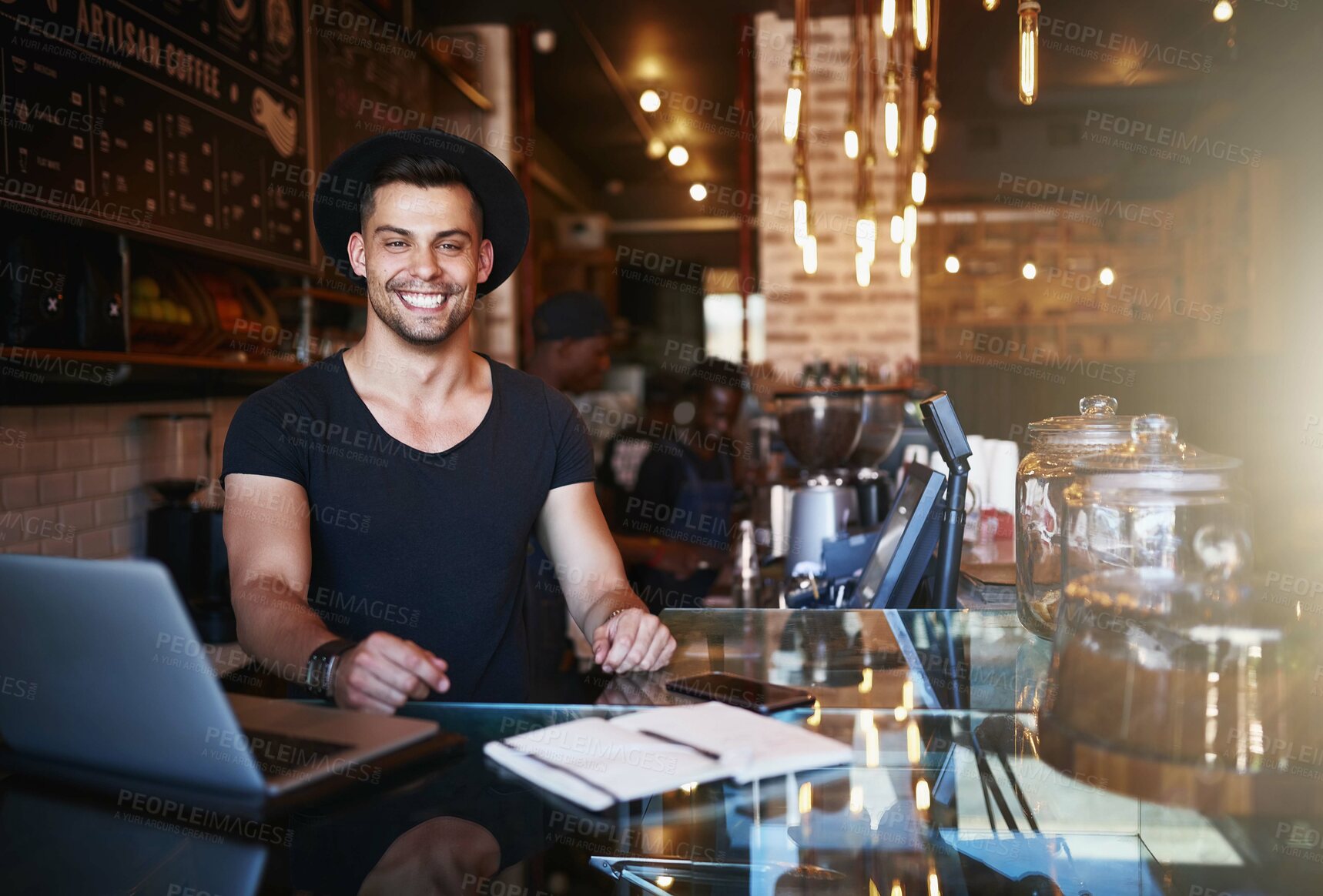 Buy stock photo Shot of a handsome young man working behind the counter of a coffee shop