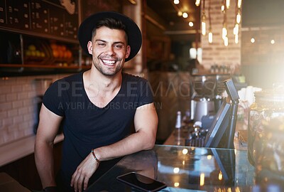 Buy stock photo Shot of a handsome young man working behind the counter of a coffee shop