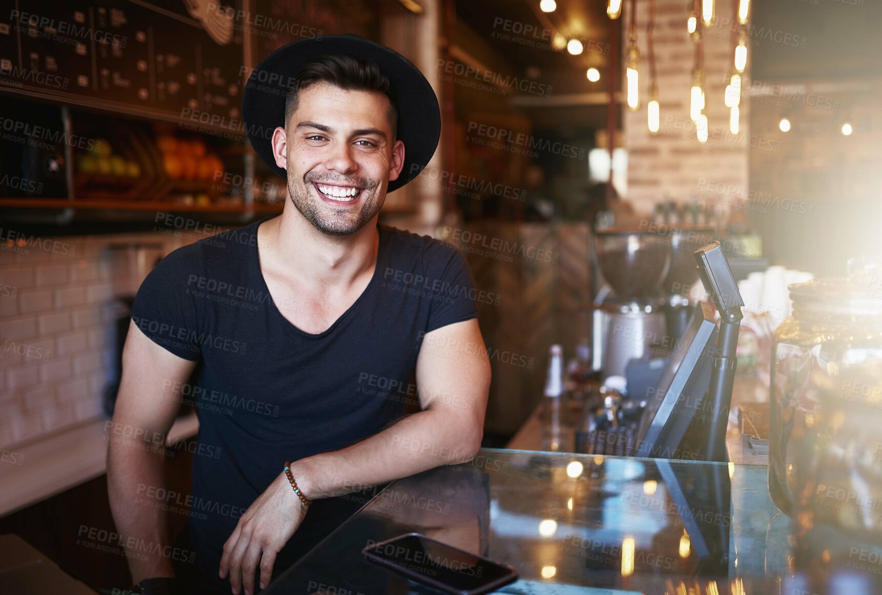 Buy stock photo Shot of a handsome young man working behind the counter of a coffee shop