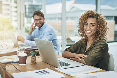 Buy stock photo Portrait of a young woman working at her desk with her colleague in the background